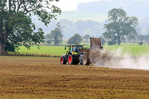 A tractor spreading fertiliser on farmland